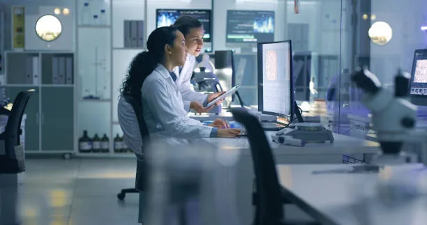 Medical researchers looking at and examining a brain scan on a computer while working late in an office employee together. Lab workers analyzing and talking about results from a checkup while working for people in government health sector.